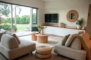 A modern living room with a sofa set, a TV, and a large window.