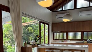 A modern living room with a sofa, a coffee table, and a kitchen area with a bar. - Malai Khaoyai (Pak Chong)