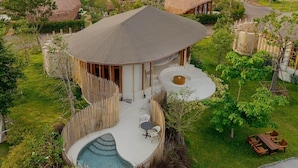A modern villa with a circular pool, surrounded by lush greenery and thatched-roof structures. - Malai Khaoyai (Pak Chong)