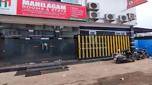 A building with a sign for 'MAMILAGAM ROOMS & STAYS' advertising amenities like A/C rooms, 24-hour water, WiFi, and more. - Mahilagam (Chennai)