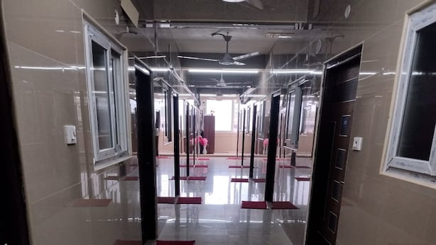 A corridor with reflective floors, red mats, and doors leading to rooms. - Mahilagam (Chennai)