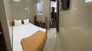 A hotel room with a large bed, a TV mounted on the wall, and a small table. - Mahilagam (Chennai)