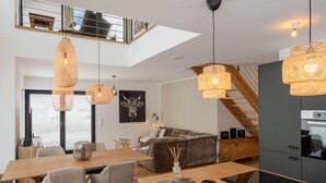 Un interno moderno con zona pranzo, divano, scalinata e cucina.