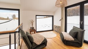 Un interno moderno con una grande finestra, un pavimento in legno e un divano verde.