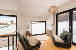 A modern interior with a large window, a wooden floor, and a green sofa.