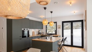 Una cucina moderna con mobili grigi, un'isola in legno e luci a sospensione.