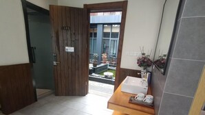 Un baño con puerta de madera, un lavamanos y una pequeña mesa con espejo.