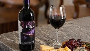 A bottle of Inizio wine, a glass of red wine, and a charcuterie board with cheese, grapes, and crackers on a kitchen counter. - Baja Toscana Private Wine CountryRetreat (Valle de Guadalupe)