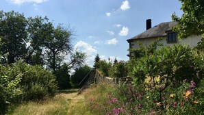 Une maison avec un mur en pierre et un escalier en bois menant à l’entrée.