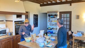 Une cuisine avec des poutres en bois, un four à micro-ondes, une étagère remplie de bouteilles et un tableau noir servant de menu.