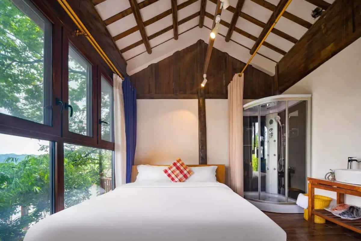 Un dormitorio con una cama grande, ducha y vistas a zonas verdes.