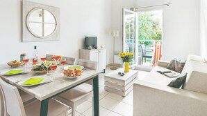 Een lichte, moderne eetruimte met een gedekte tafel, een televisie en uitzicht op de omgeving.