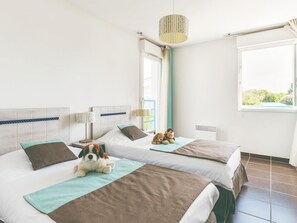 A hotel room with two beds, a window, a hanging light fixture, and a view of greenery outside. - Appealing Apartment With Sauna (Saint-Palais-sur-Mer)