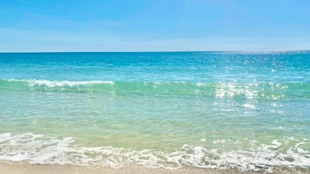 A beach with clear turquoise water and gentle waves. - Rookery 3 family friendly pools beach dogs (Gulf Shores)