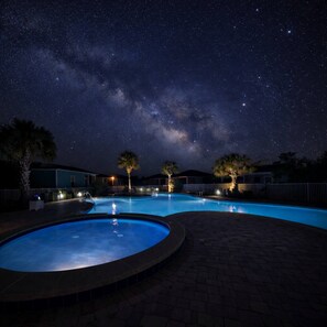 Ein Schwimmbecken bei Nacht unter einem Sternenhimmel.