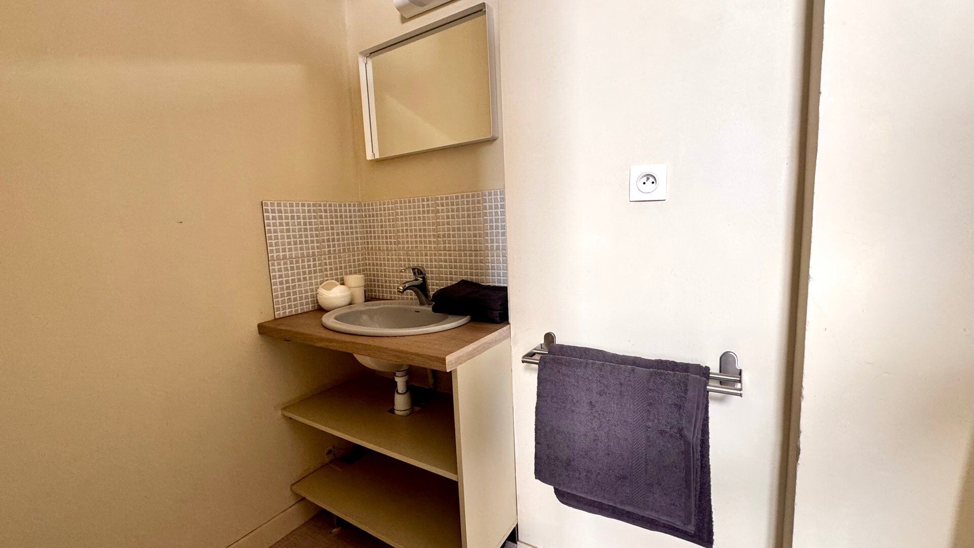 Une petite salle de bain avec un lavabo, un miroir et un porte-serviettes.