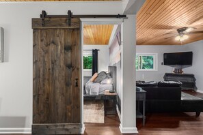 Een kamer met een bed, een bureau, een televisie en een schuifdeur in boerderijstijl.
