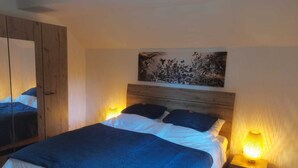 Un dormitorio con cama, lámparas de noche, un espejo y un adorno en la pared.