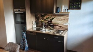 Cocina compacta con alacenas oscuras, horno empotrado, pileta y cocina.