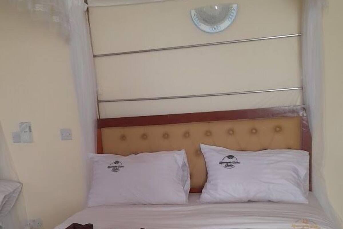 Una cama individual con cabecera, dos almohadas y dosel.