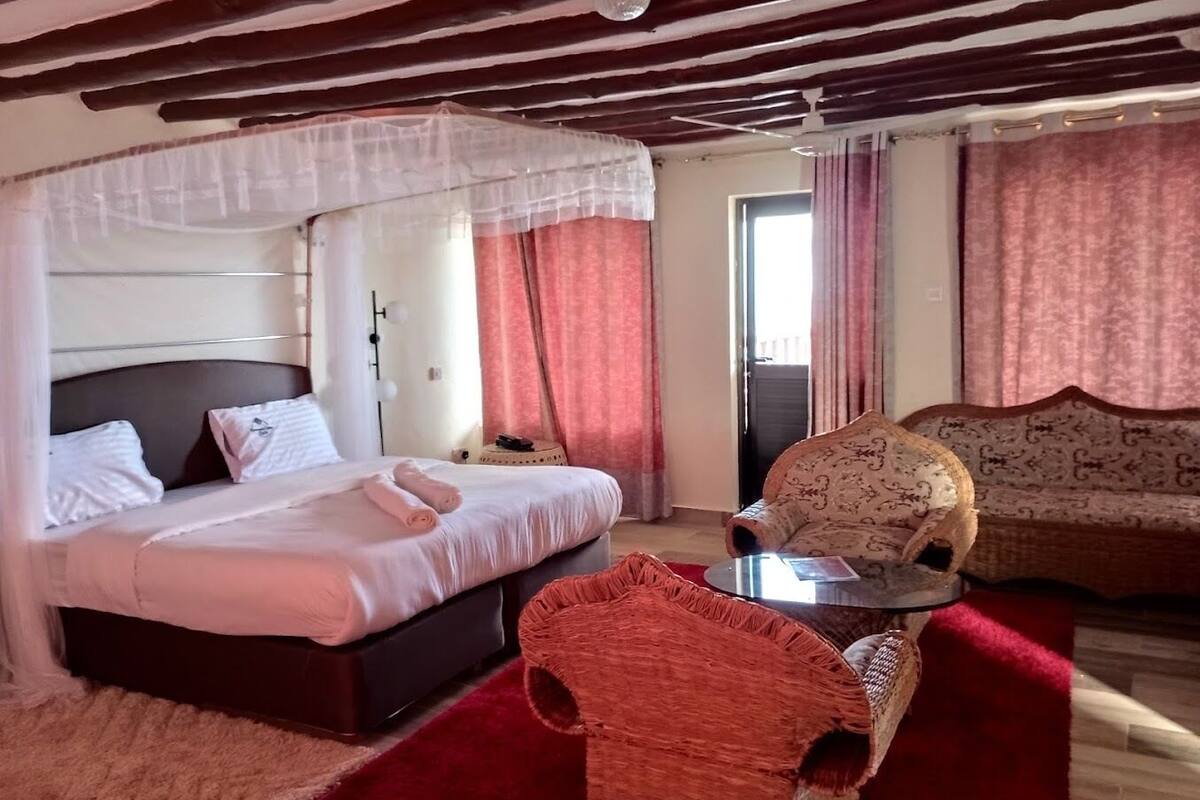 Una habitación con cama, una silla, un sofá y una ventana.