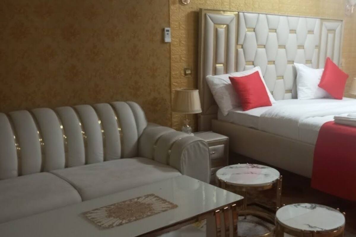 Una habitación de hotel con una cama, un sofá, una mesita y dos mesitas auxiliares.