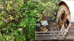 A wooden deck with a table and chairs, surrounded by dense foliage.