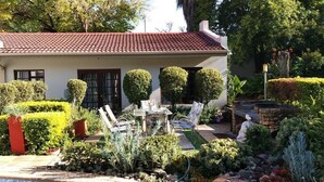 Ein Haus mit rotem Ziegeldach, einem Swimmingpool und gepflegten Gärten.