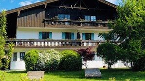 Un bâtiment en bois à deux étages, doté d’un balcon et entouré de verdure.