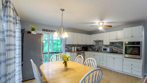 Una cocina moderna con armarios blancos, una mesa de comedor de madera y un ventilador de techo.