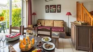 Un coin repas avec une table dressée pour deux personnes, un canapé et un escalier.