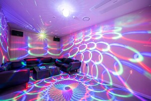 A room with a sofa, a coffee table, and a wall projection of colorful light patterns.