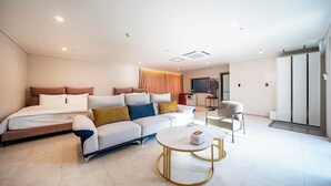 Una habitación de hotel moderna con una cama, un sofá, una mesita de centro redonda y un escritorio pequeño.