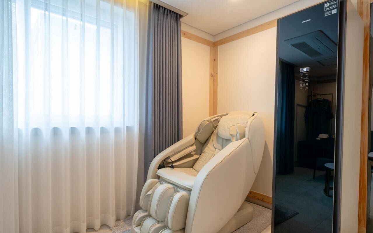 Una silla de masajes en una habitación de hotel con vista al exterior a través de una ventana.
