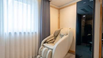 Una silla de masajes en una habitación de hotel con vista al exterior a través de una ventana.
