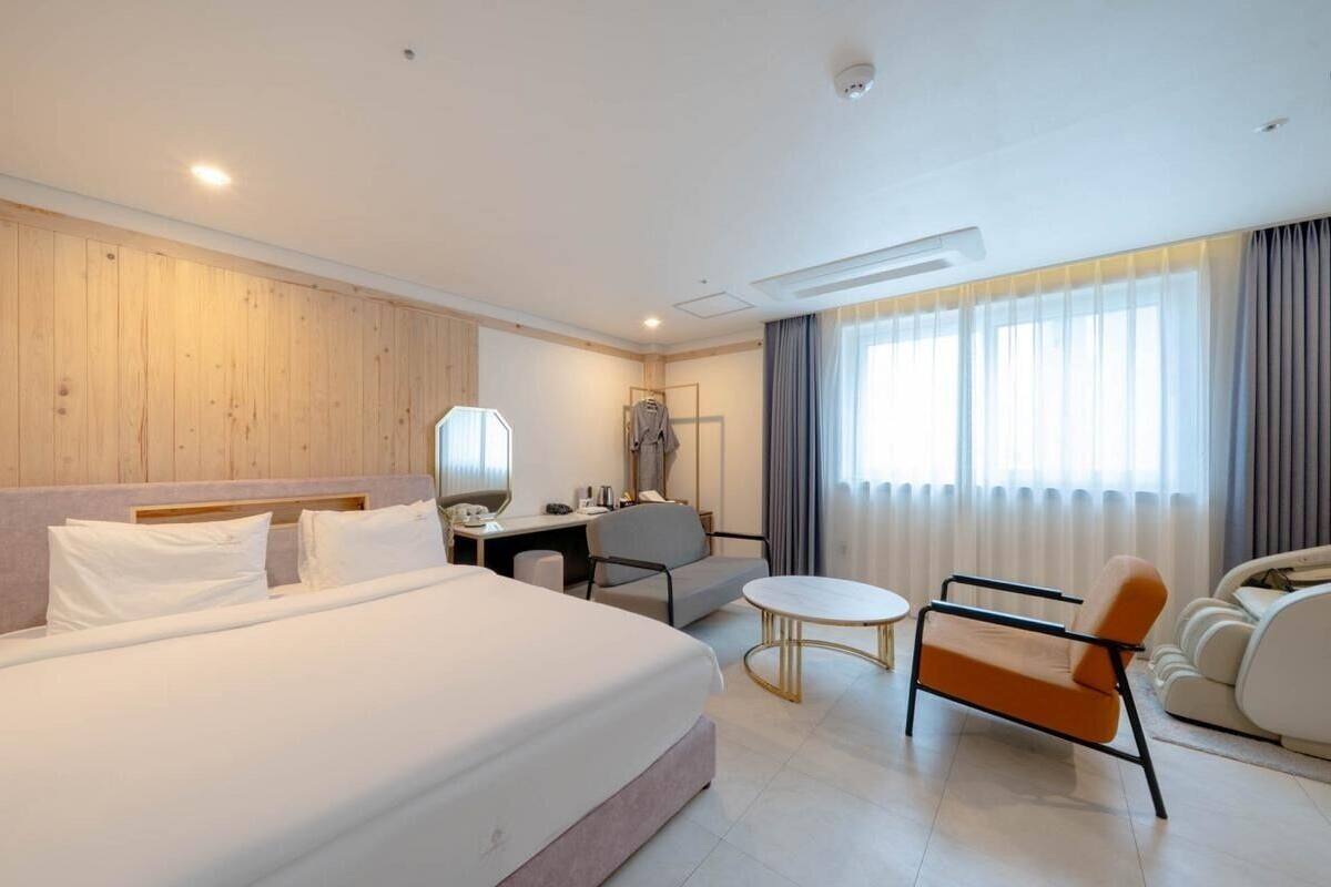 A hotel room with a large bed, a desk, a chair, a round table, and a sofa.