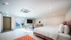 Una habitación de hotel moderna con una cama grande, un televisor de pantalla plana y un puerta corrediza de vidrio que da a un balcón.