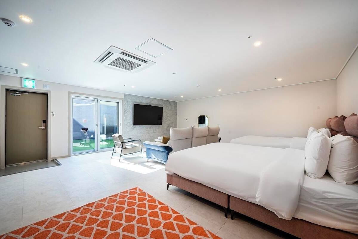 A modern hotel room with a large bed, a flat-screen TV, and a sliding glass door leading to a balcony.