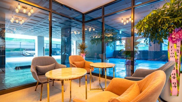 Un interior moderno con paredes de vidrio, una zona de estar con mesas redondas y vistas a un aparcamiento.