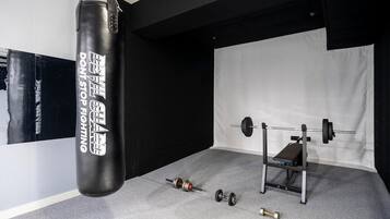 A gym with a punching bag, a barbell, and dumbbells.