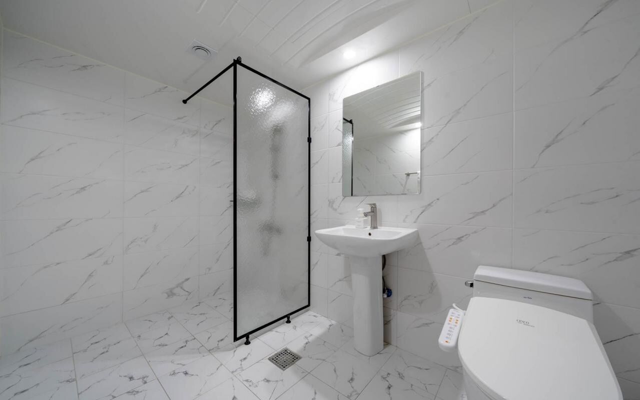 A bathroom with a glass-enclosed shower, a pedestal sink, and a toilet.