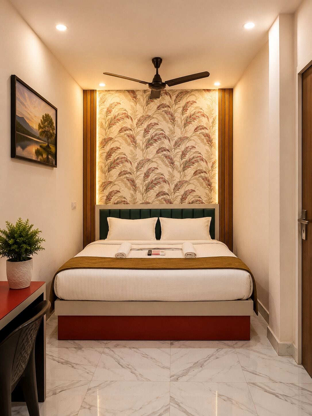 A hotel room with a bed, a ceiling fan, a nightstand with a plant, and a painting on the wall.