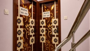 Pasillo de hotel con dos puertas, una indica 'ROOM NO-101' y la otra 'ROOM NO-102'.