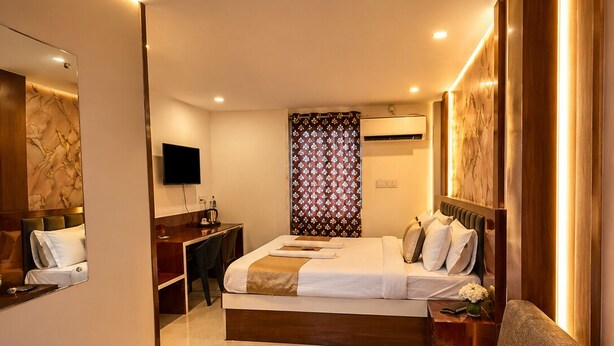 Una habitación de hotel moderna con cama, sofá, escritorio, televisor y mesa de centro con una revista.