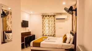 Una habitación de hotel moderna con cama, mesita de noche, sillón, sofá y televisor.
