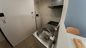 A compact kitchen with a sink, microwave, and stove. - Ashe Maison Tennoji West II (Osaka)