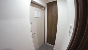A narrow hallway with a door on the left and a wooden door on the right. - Ashe Maison Tennoji West II (Osaka)