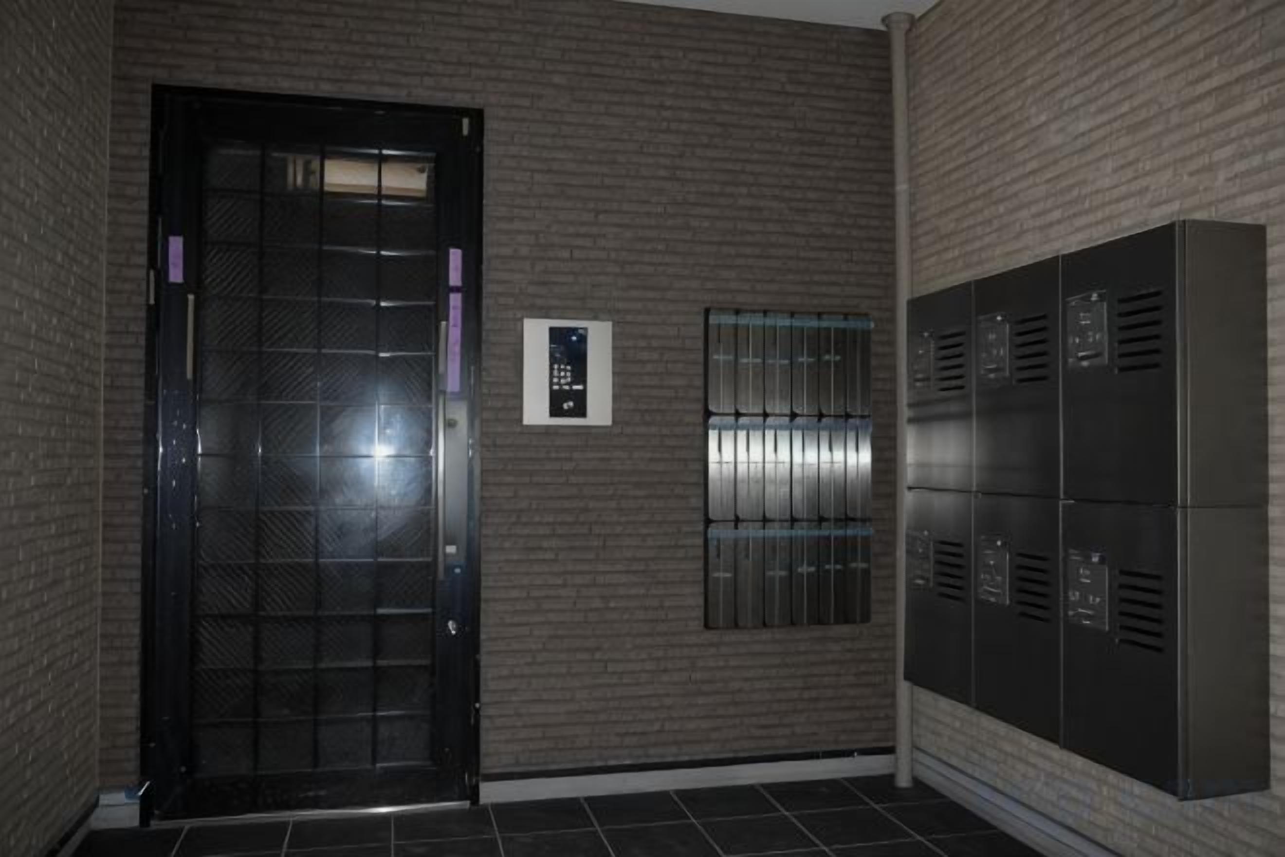 A hallway with a door, a keypad, and a row of lockers.