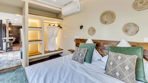 Una camera d'albergo con un letto, un armadio, uno specchio e un condizionatore d'aria a parete.