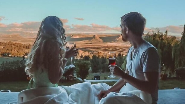 A couple sitting on a bed with a view of a landscape. - Fat Mulberry Guest Farm (Fouriesburg)